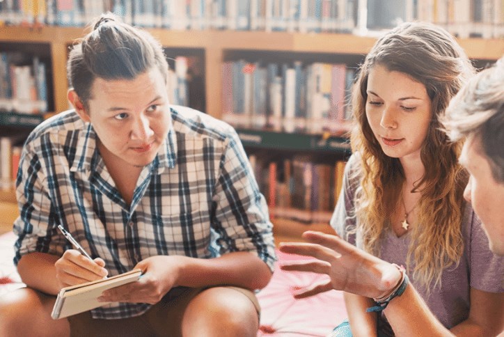 Three teens in a library brainstorming